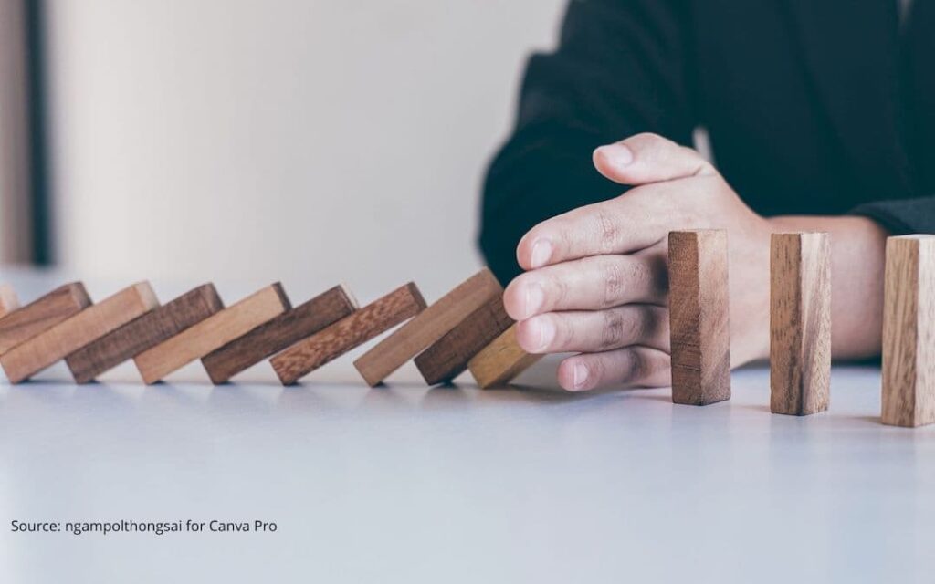 Person stopping dominos from falling to illustrate redefining success.