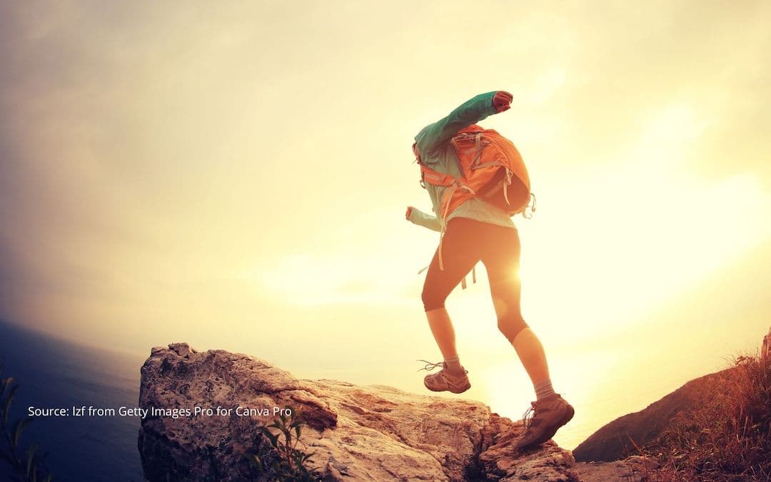 Person about to reach the top of a mountain to illustrate redefining success.