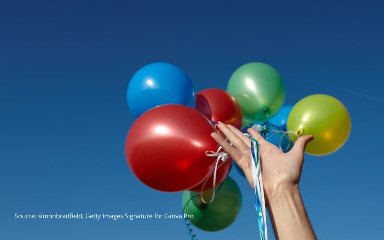 Hand releasing colorful balloons to illustrate how to let go of the past.