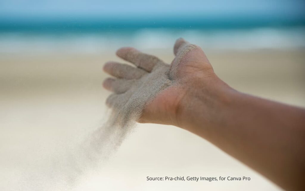 Hand releasing sand to illustrate concept of letting go of preconceived notions of your identity.